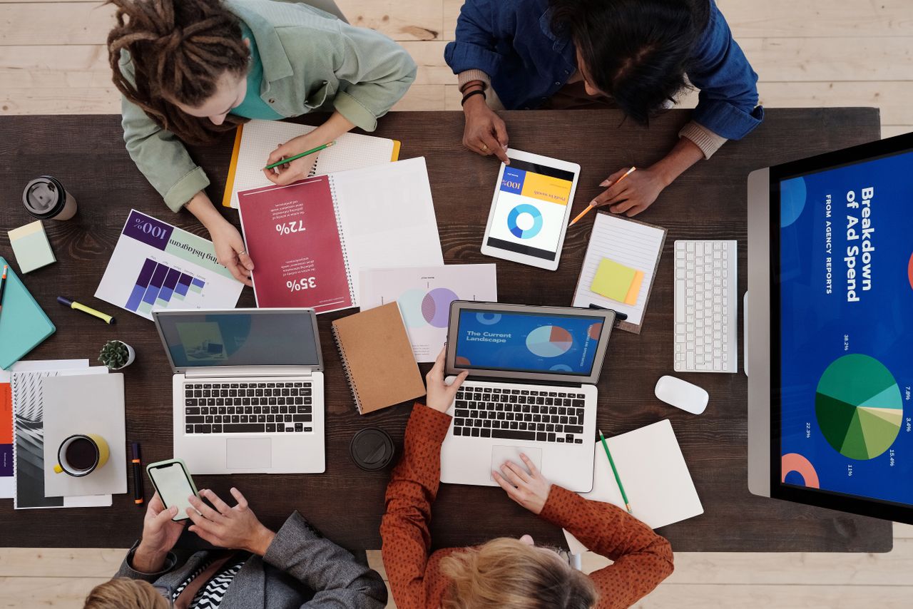Une équipe variée travaillant ensemble sur des stratégies de marketing numérique autour d’une table, avec des ordinateurs portables et des tablettes.