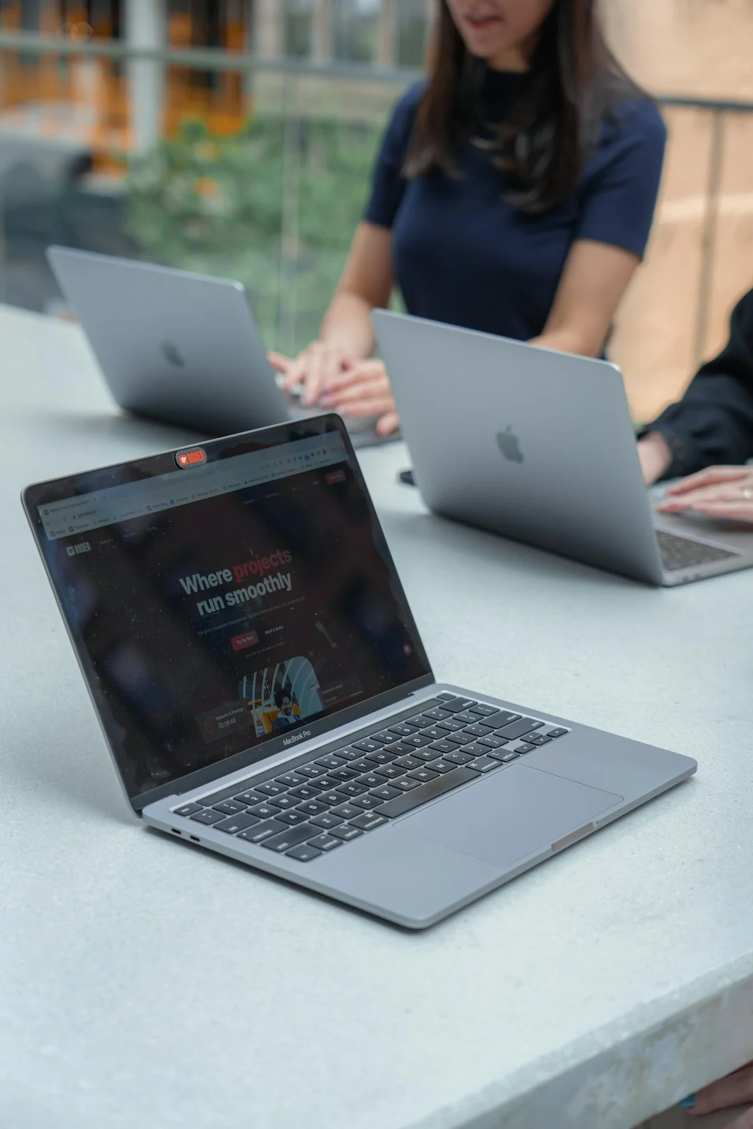 Hands holding a smartphone next to a laptop displaying stock charts, highlighting digital trading.