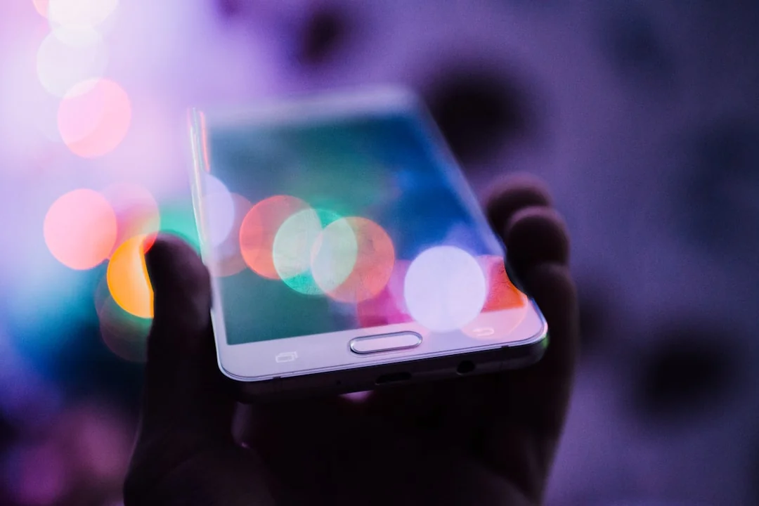 Deux hommes d’affaires analysent des données boursières à l’aide d’un smartphone et d’un ordinateur portable dans un bureau moderne.